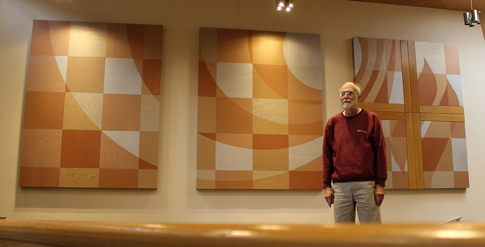 Bob standing in front of the three large wooden panels in Zion's sanctuary